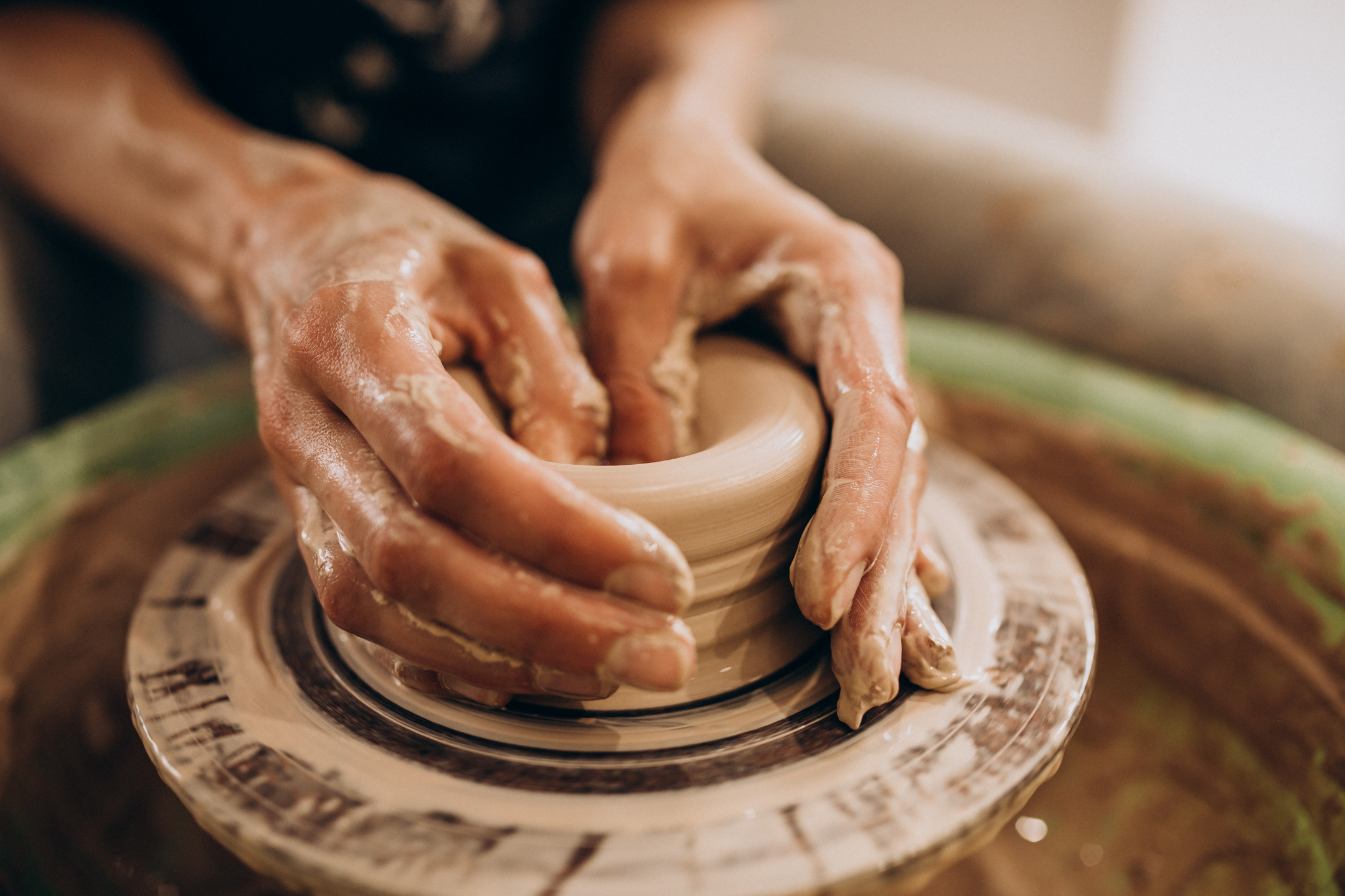 Woman craftmaster hands throwing pot on pottery wheel